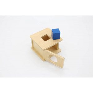 Material sestavlja lesena škatla s kvadratno režo. Otrok doživi izkušnjo stalnosti predmeta, prvič v rokah drži telo-obliko valja. Področje: fina